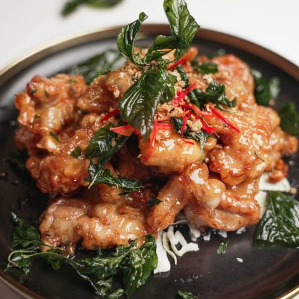 Noi Thai Cuisine's crispy chicken with basil, chili, and garlic on a dark plate.